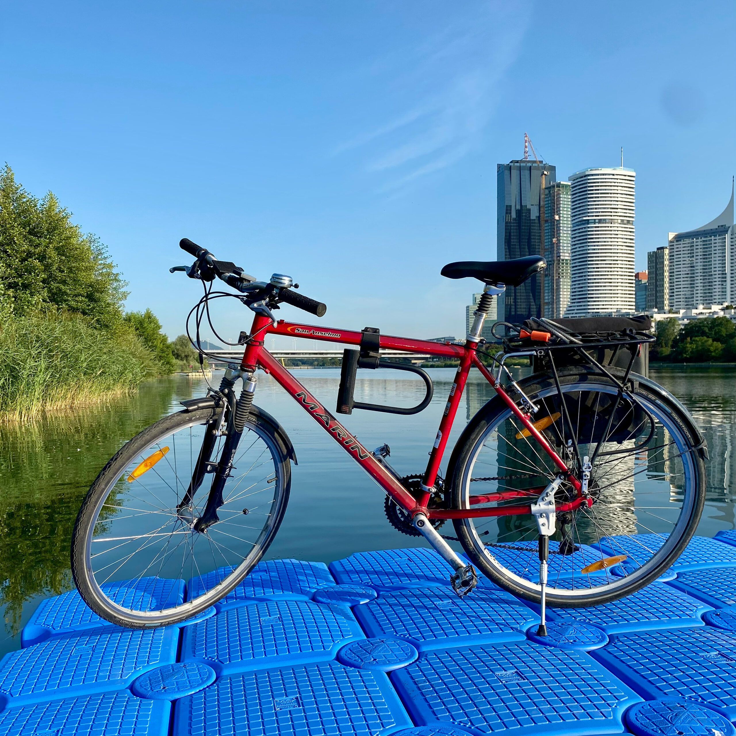 Ein Fahrrad steht auf einer schwimmenden Plattform auf der Wiener Neuen Donau, dahinter die Donaucity