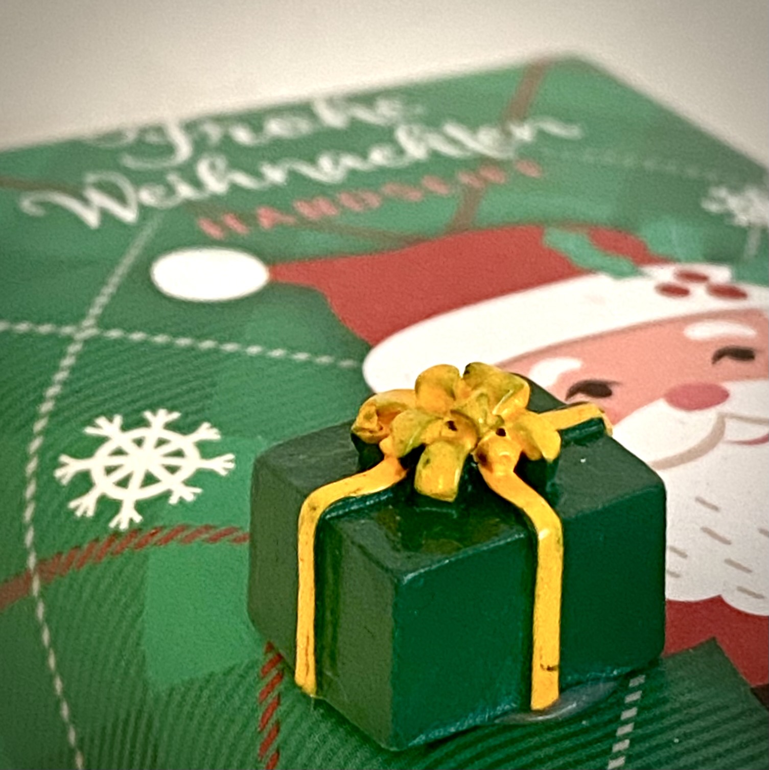 Ein winziges Geschenkspäckchen auf einer Karte mit der Aufschrift: Frohe Weihnachten, dazu ein gezeichneter Weihnachtsmann