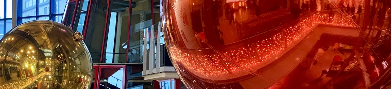 Rote und goldene Kugel, darin Spiegelungen von Weihnachtsdeko