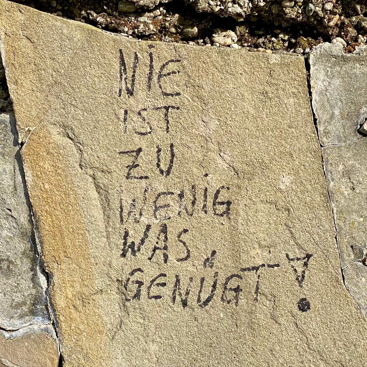 Eine Steinplatte mit der Aufschrift "Nie ist zu wenig was genügt!"