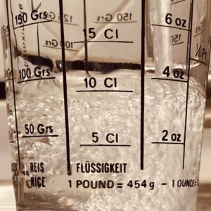 Ein Glas mit Messskalen, in das Wasser hineinsprudelt