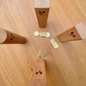 Vier Holzklötze von oben, vor drei von ihnen liegen 4, 3 und 3 Geldmünzen