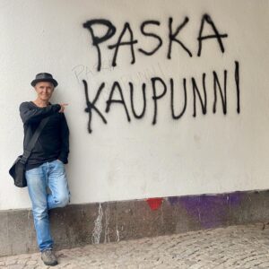Das Bild zeigt Stefan Peters neben einem Graffiti mit der Aufschrift Paska Kaupunni