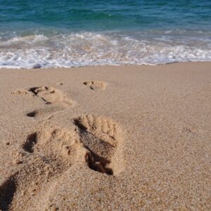 Fußabrücke im Sandstrand, dahinter das Meer
